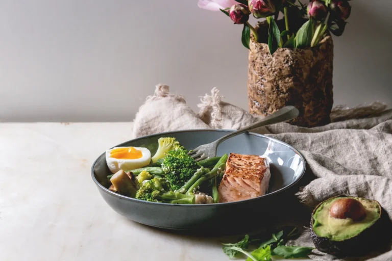 Kom met zalm, broccoli, boontjes en een ei op een linnen doek