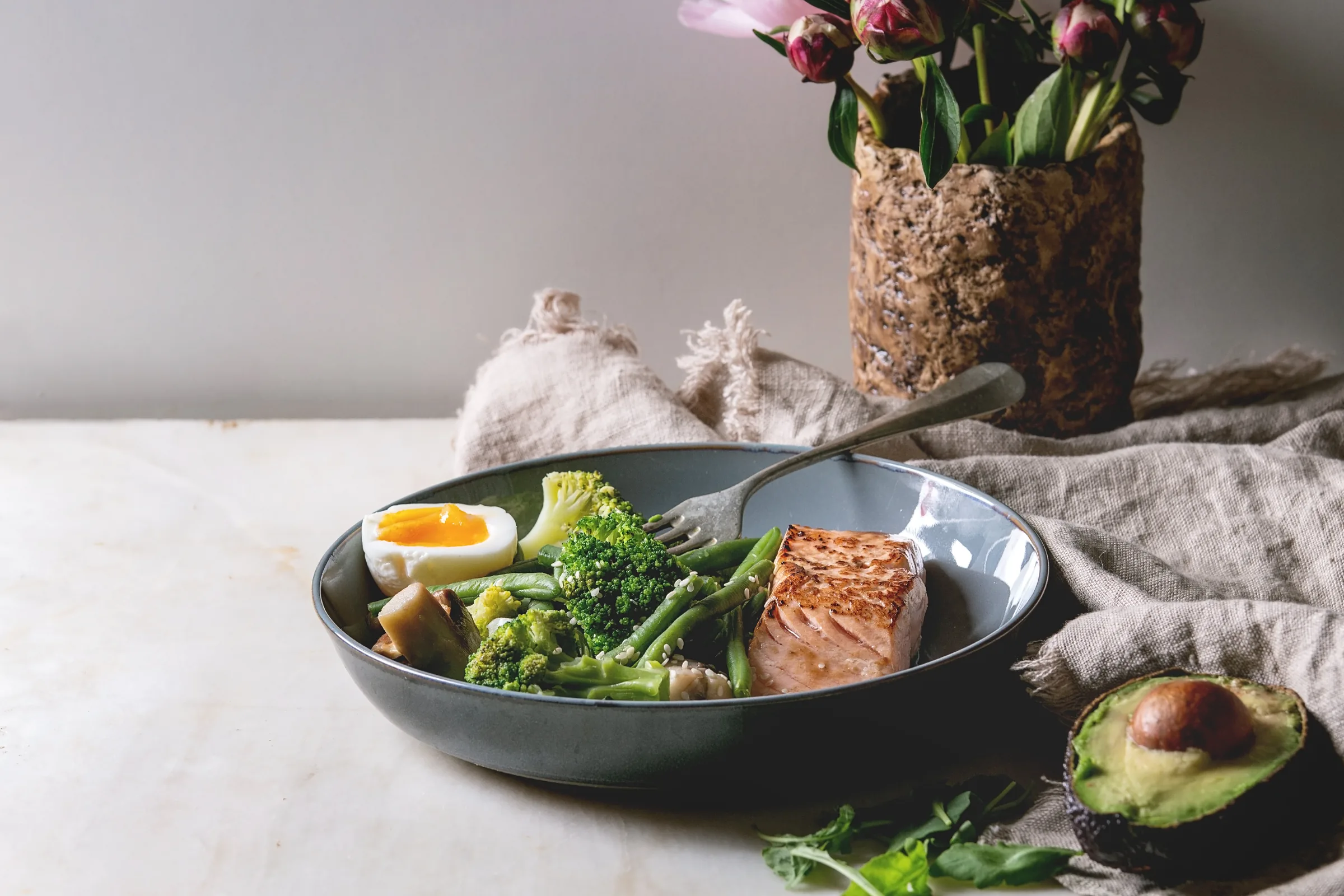 Kom met zalm, broccoli, boontjes en een ei op een linnen doek