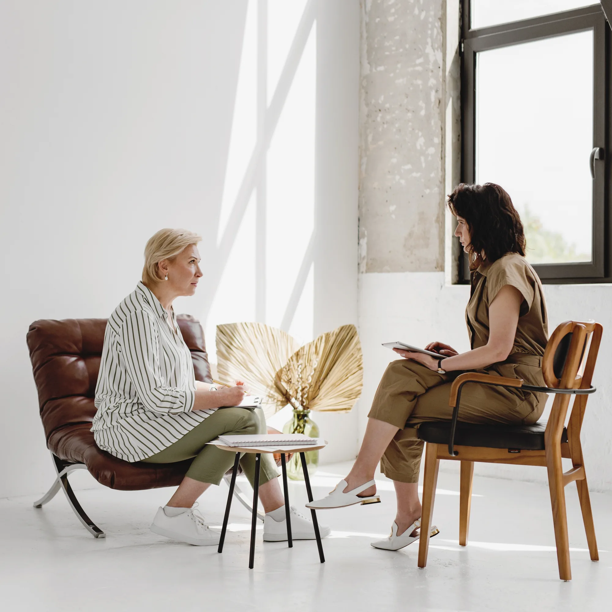 Twee vrouwen in gesprek aan een klein tafeltje in een lichte ruimte