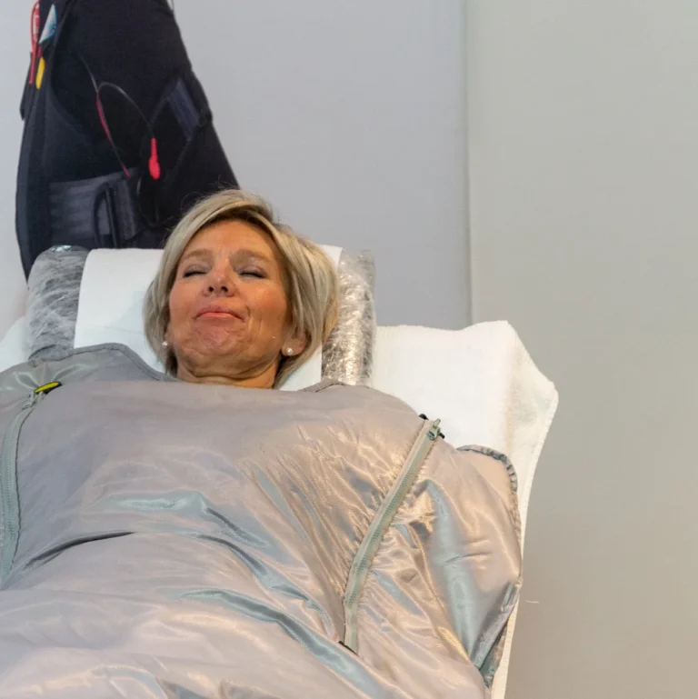Vrouw ontspant met gesloten ogen onder de zilveren infrarood warmtedeken in de studio van Focus-On