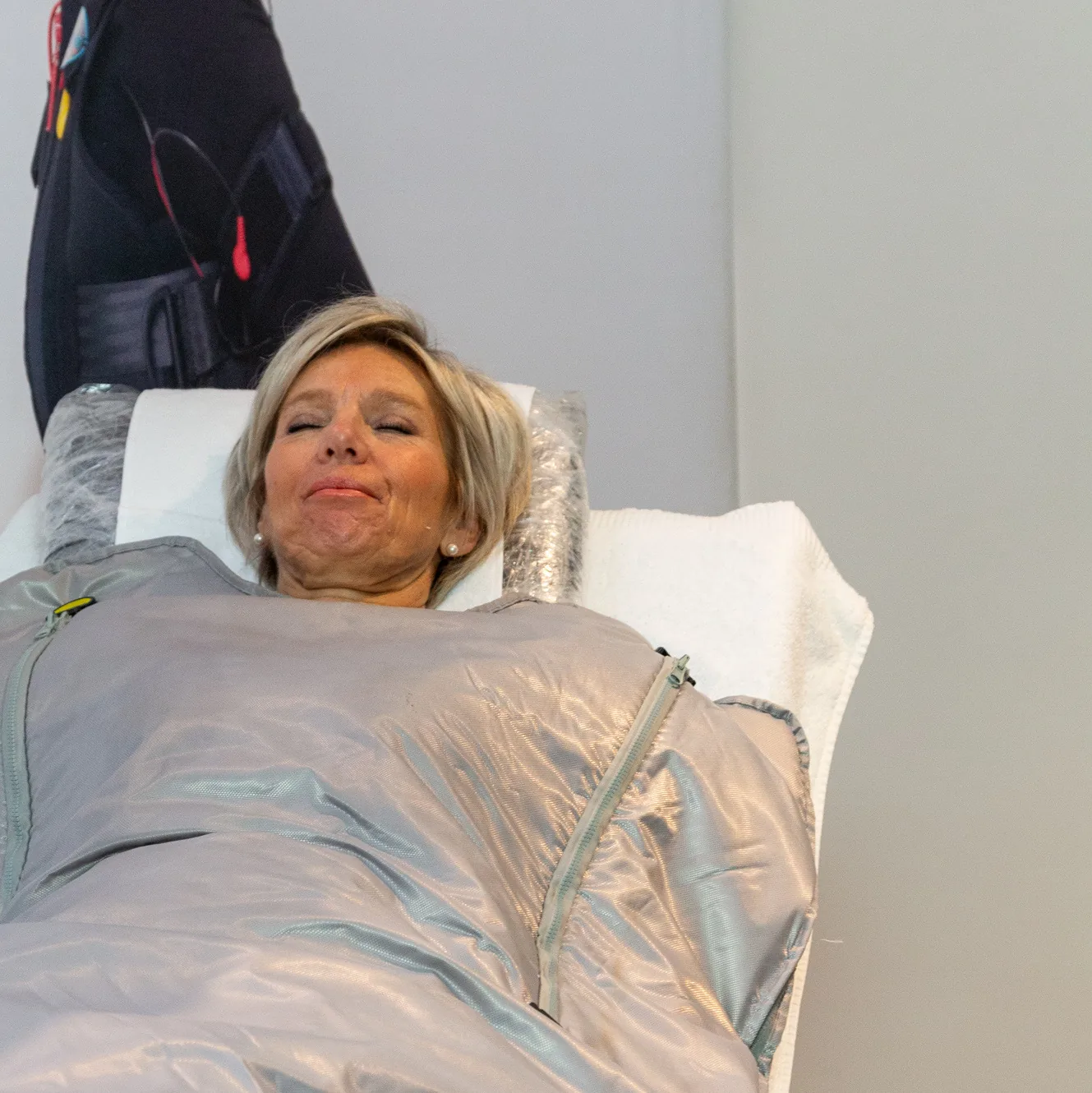 Vrouw ontspant met gesloten ogen onder de zilveren infrarood warmtedeken in de studio van Focus-On