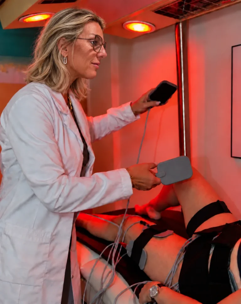 Kitty Goedgezelschap stelt een toestel in tijdens een behandeling met elektroden en rood licht