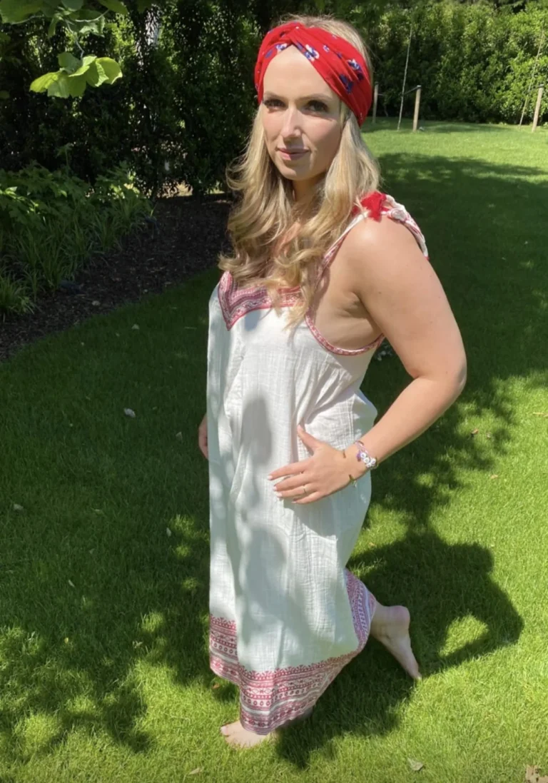 Sofie lacht in de tuin, met een rode haarband