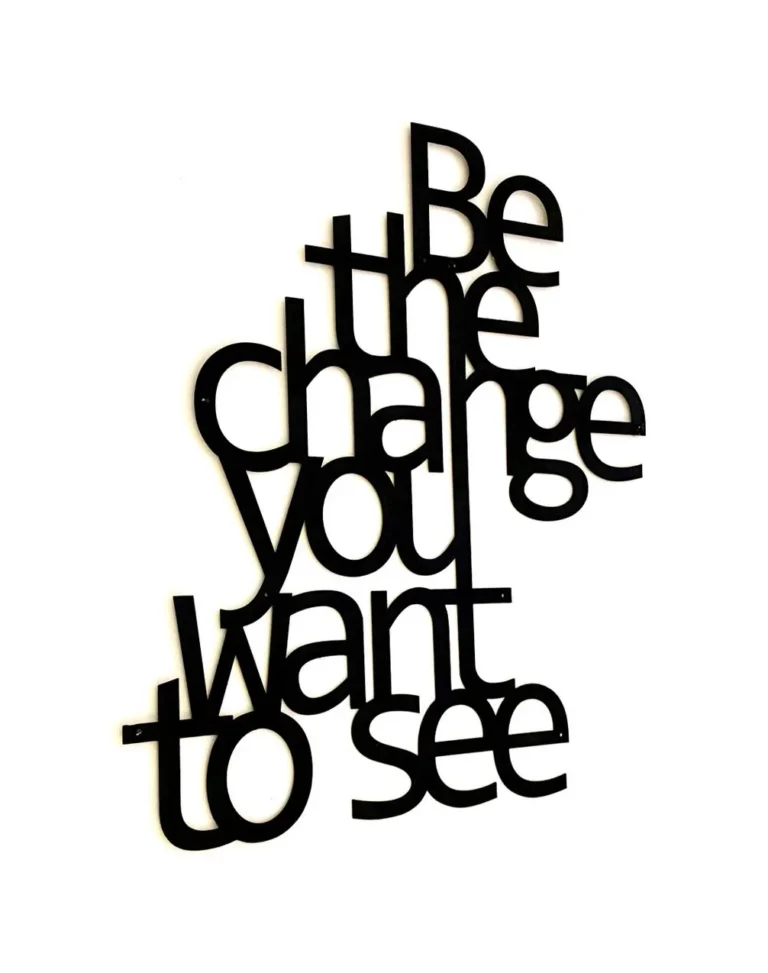 Zwarte wandtekst Be the change you want to see op een witte muur